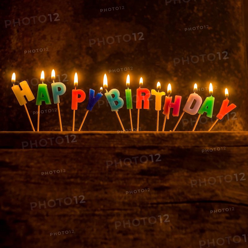 Brightly lit birthday candle arrangement spelling out Happy Birthday on a rustic wooden surface for a joyful celebration moment