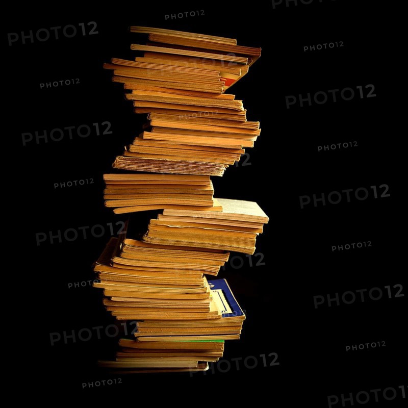 Stack of neatly organized books arranged vertically against a dark backdrop highlighting their unique shapes and textures