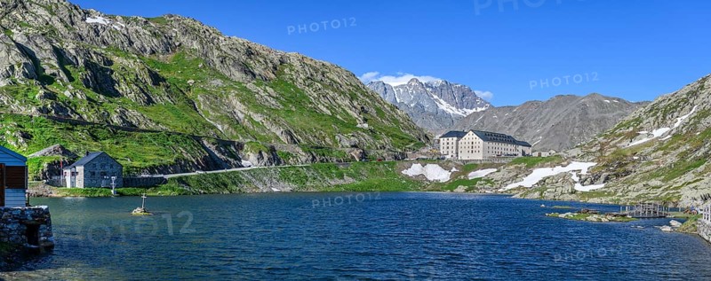 Panoramic photo of mountain lake Alpine lake Lac du Grand Gd Saint St Bernard, on the left Swiss border station border building for passport control, centre in the background building with hostel Auberge and hospice Hospice on Alpine pass Great Saint Bernard Col du Grand Gd Saint St Bernard Colle del Gran San Bernardo, region Valle d'Aosta, Italy, canton Valais, Switzerland