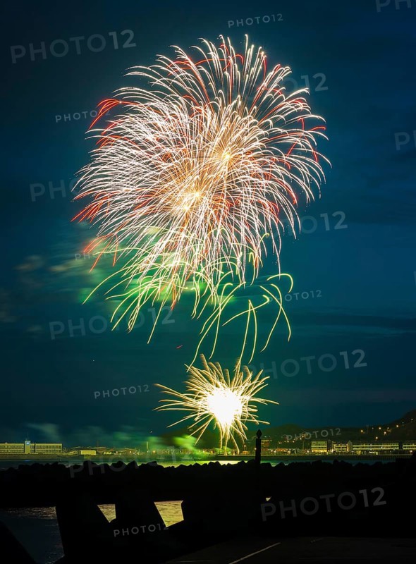 Brilliantly shining, atmospheric, intense fireworks in red, green and gold, Heligoland island festival, nocturnal lowlands, inland harbour, jetty and lobster shacks, midland, in front the tetrapod dune platforms and the reflecting waters of the North Sea, Night sky at the island festival in summer, symbolic image also for New Year's Eve, New Year's Eve fireworks, bright, colourful, many colourful traces of light, sparks, lively glitter, night, Heligoland Island, Schleswig-Holstein, Germany
