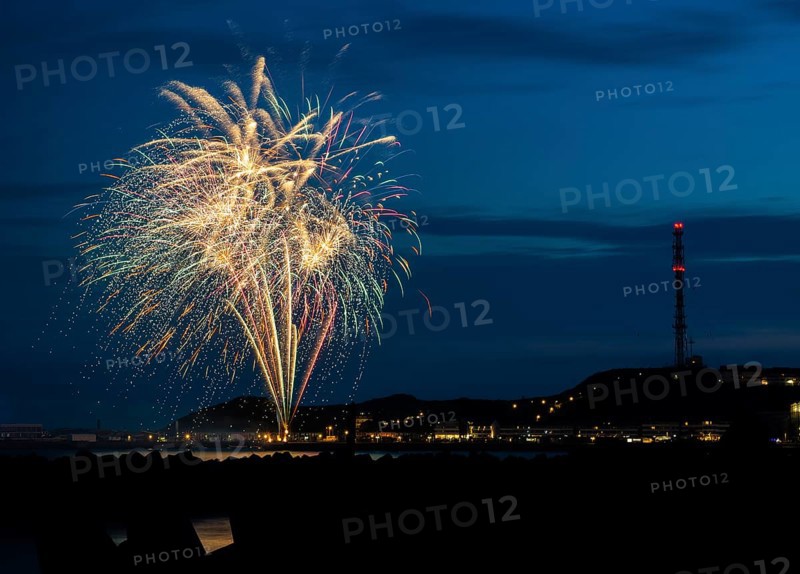 Brilliant, atmospheric fireworks display for the Heligoland island festival in red, green and gold, nocturnal lowlands with inland harbour, jetty and lobster shacks, on the right the uplands with transmission tower, transmitter, in front the groynes of the dune, reflecting water of the North Sea, night sky at the island festival in summer, symbolic image also for New Year's Eve, New Year's Eve fireworks, bright, colourful, many colourful traces of light, sparks, lively glitter, night, island of Heligoland, Schleswig-Holstein, Germany