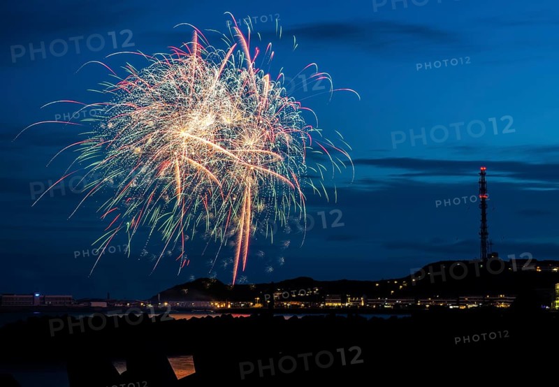 Brilliant, atmospheric fireworks display for the Heligoland island festival in red, blue and gold, nocturnal lowlands with inland harbour, jetty and lobster shacks, on the right the uplands with transmission tower, transmitter, in front the groynes of the dune, reflecting water of the North Sea, blue night sky at the island festival in summer, symbolic image also for New Year's Eve, New Year's Eve fireworks, bright, colourful, many colourful traces of light, sparks, lively glitter, night, Heligoland Island, Schleswig-Holstein, Germany