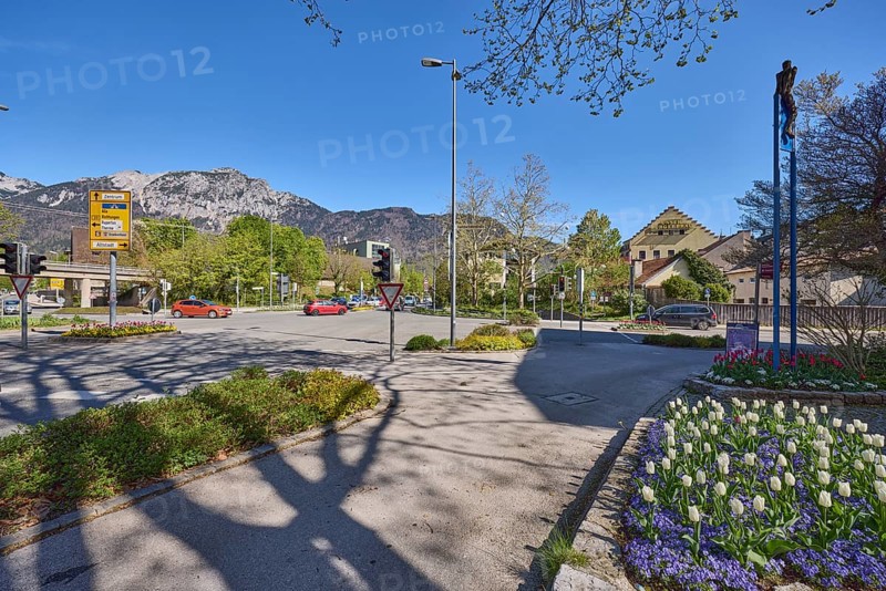Streets, traffic lights, lantern, trees, flower bed, tulips (Tulipa), general architecture, mountain landscape, mountains, shadow, blue sky, cirrostratus clouds, federal highway 20, intersection between Anton-Winkler-Straße, Innsbrucker Straße, Kammerbotenstraße and Reichenbachstraße, Bad Reichenhall, district Berchtesgadener Land, Bavaria, Germany