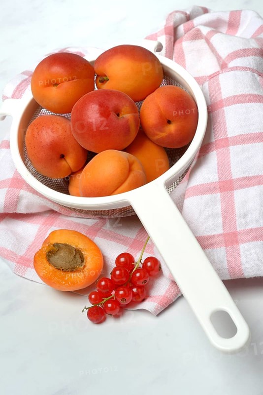 Apricots in a colander and redcurrants