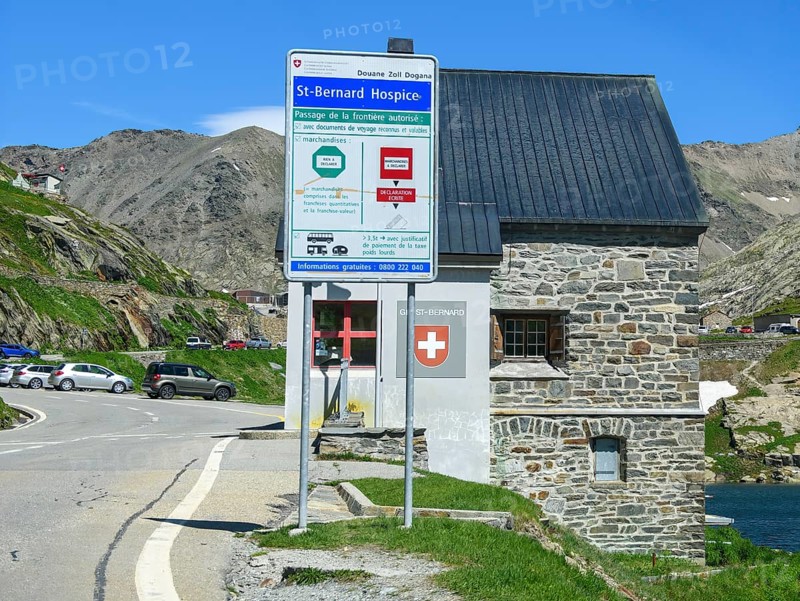 View of front sign with information for customs clearance at historic Swiss border building Border station Checkpoint for passport control Identity check Customs at border pass Road crossing National border State border Italy and Switzerland on the shore of Lac du Grand St-Bernard, Great Saint Bernard Pass, Colle del Gran San Bernardo, Col du Grand Saint Bernard, Valais, Switzerland