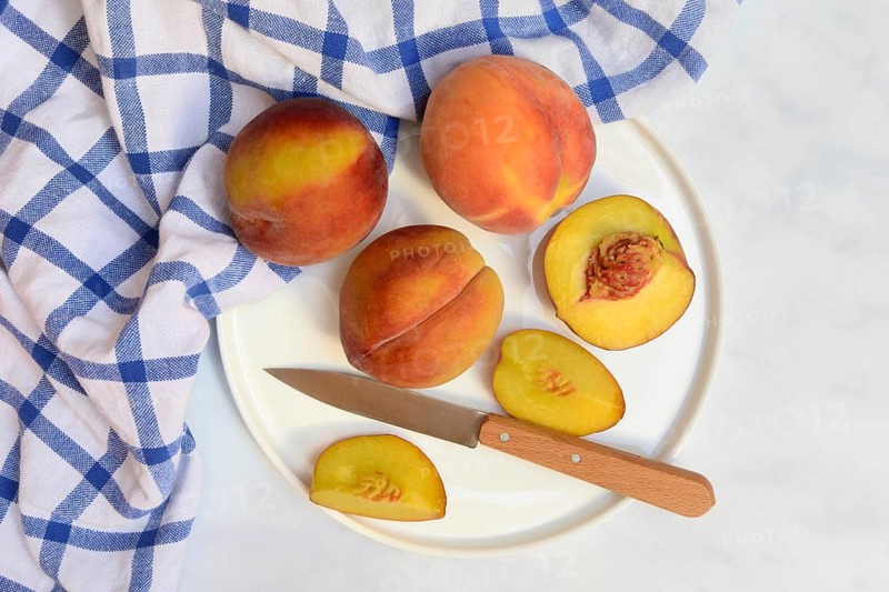 Peach with knife on plate, peach halves, Prunus persica