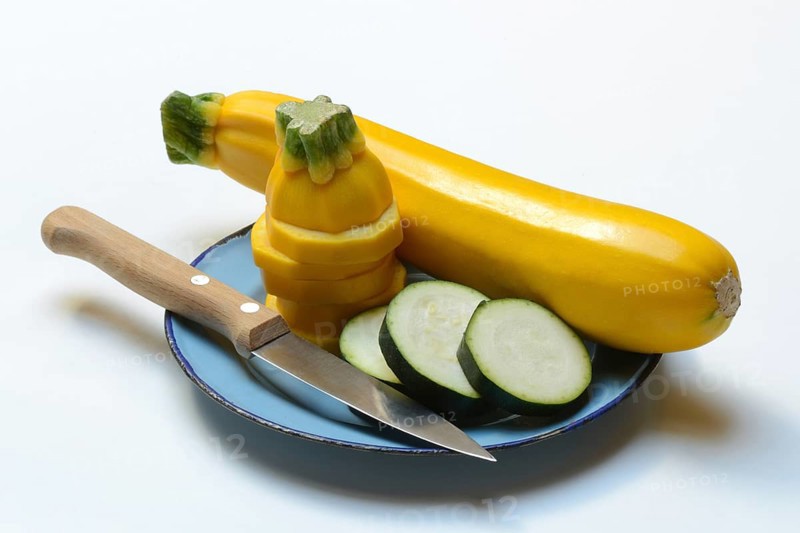 Green and yellow courgettes on a plate with a knife, Cucurbita pepo