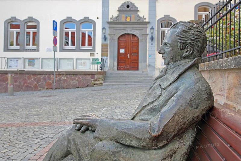 Johann Wolfgang von Goethe by Klaus Gutting sitting on the bench, arms, bronze sculpture, looking, monument, modern art, GoetheStadtMuseum, Amtshaus, town hall, door, market place, Ilmenau, Thuringian Forest, Thuringia, Germany