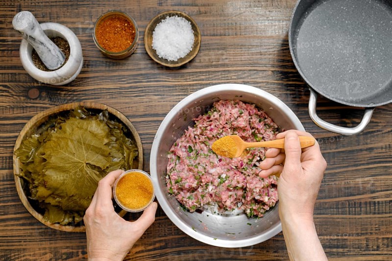 Preparing dolma involves mixing ground meat with herbs and spices before rolling it in grape leaves. This homemade dish showcases traditional culinary techniques and fresh ingredients
