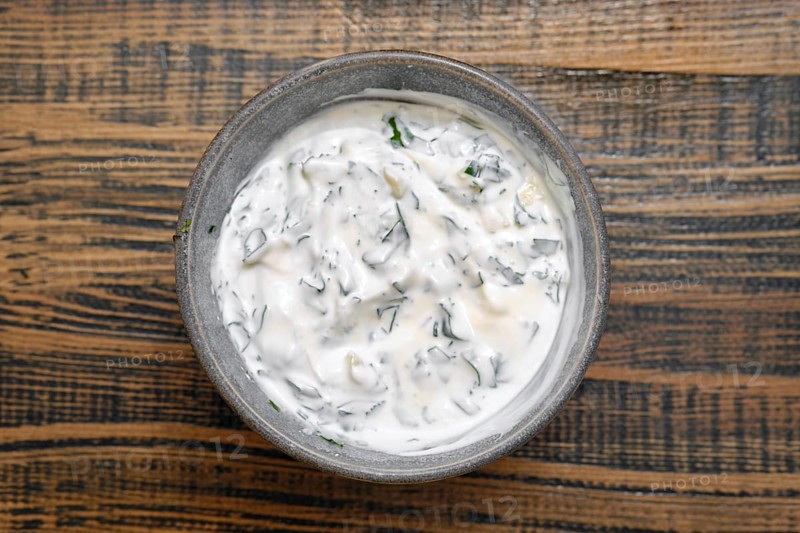 Overhead view of a bowl with sour cream mixed with chopped parsley, cilantro and garlik. Classic dipping sauce