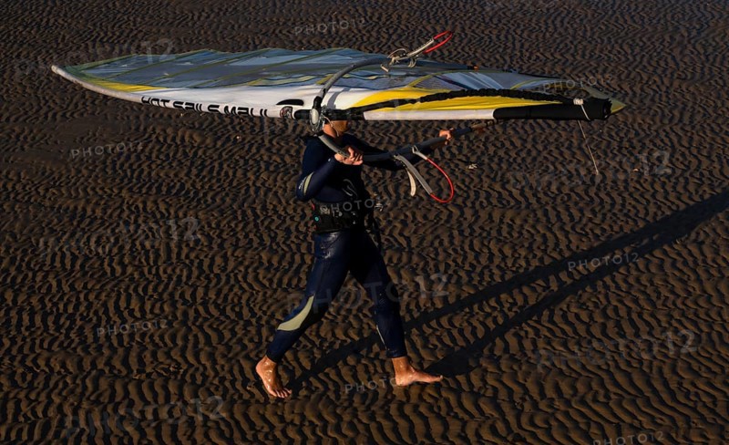 Surfer carrying his board, surfboard, over his head, beach, sandy beach, low tide, evening light, Grandcamp-Maisy, Normandy, Calvados, France