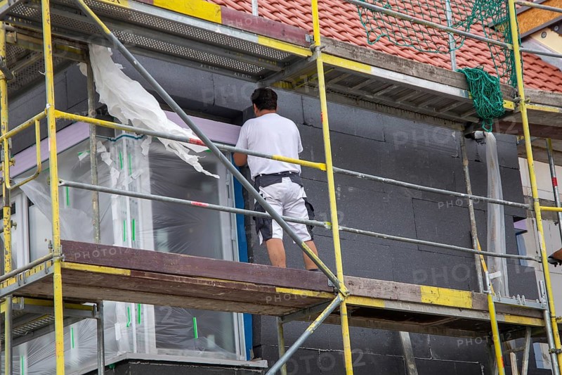 Construction workers insulate a house facade