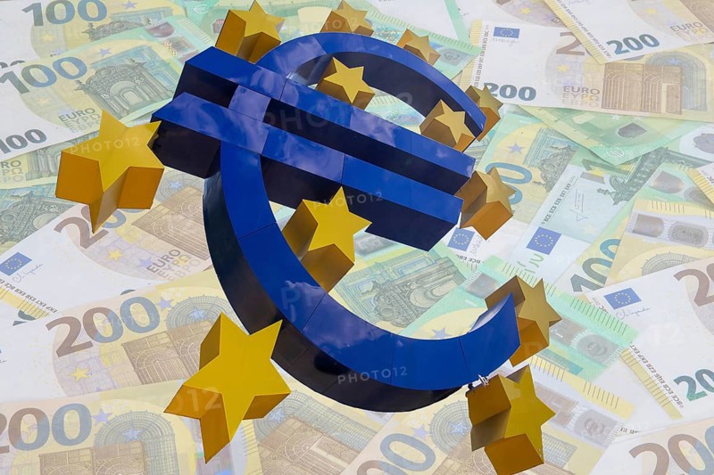 (Photomontage) euro sculpture cropped in front of euro banknotes
