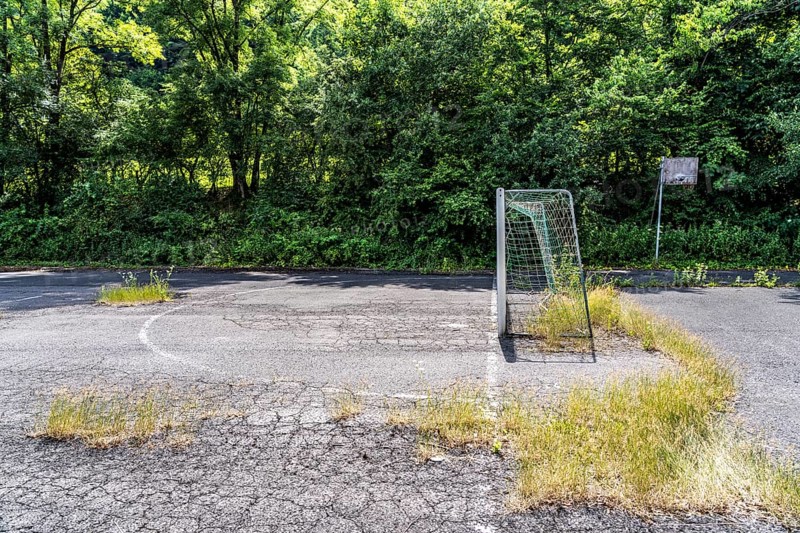 Old sports field, with asphalt floor, weeds reclaiming the field, apparently abandoned football pitch in Schmallenberg-Dorlar, in the Hochsauerland district, North Rhine-Westphalia, Germany
