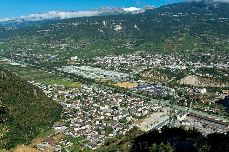 The towns of Chippis, foreground, and Sierre, background, in the Rhone Valley, the production facilities of the aluminium company Novelis Switzerland SA in the centre of the picture, Sierre, Valais, Switzerland