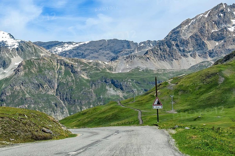 Northern pass road Mountain road from Col de l'Iseran Alpine pass to Val d'Isere Val-d'isere above tree line, on the right warning sign Traffic sign Rockfall over 2 two kilometres, Col de l'Iseran, departmental road D902, Route des Grandes Alpes, Département Savoie, Region Auvergne-Rhône-Alpes, Graian Alps, France