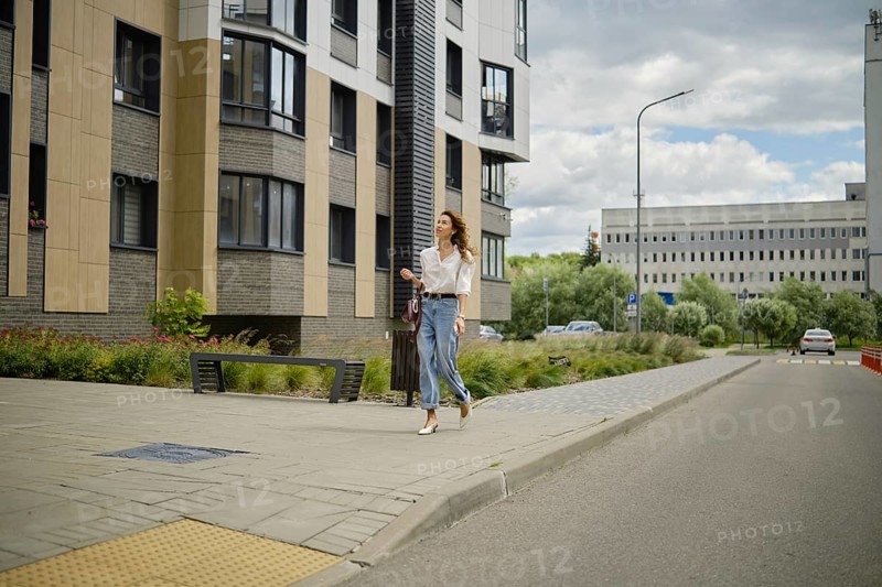 Woman strolling along the street in urban area with modern architecture on a cloudy afternoon