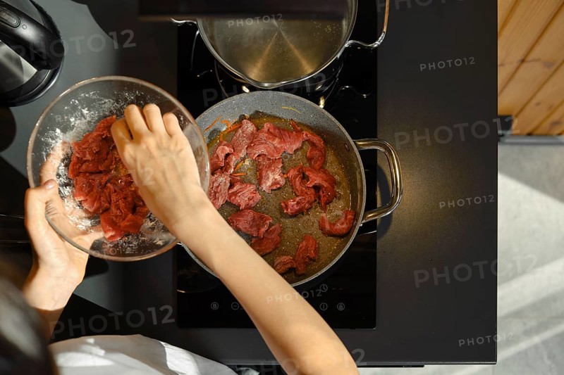 Slicing lean beef into strips and adding it to a hot pan, this skilled cook is preparing a healthy meal