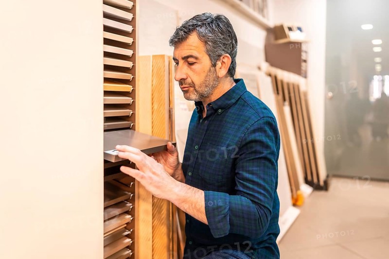 Carpenter selecting samples of wooden and metallic materials in a home improvement store for his next project