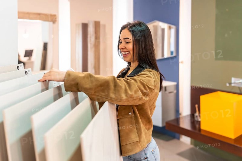 Smiling woman selecting ceramic tiles in a home improvement store, planning a bathroom renovation project