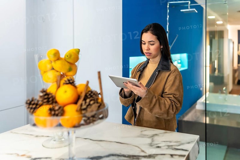 Interior designer using digital tablet while working in bathroom decor section of home improvement store showroom