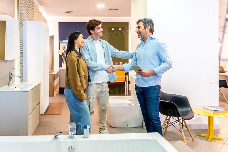 Couple shaking hands with salesman in a bathroom furniture store, finalizing purchase agreement