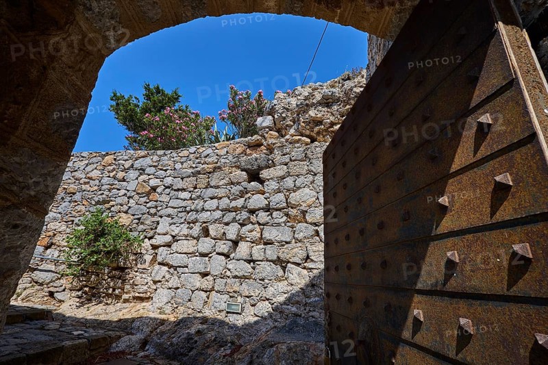 View through open Tor tor to stone wall crowned by flowers, blue sky visible, Open entrance gate, Pandeli Castle, Castle, Leros Fortress, St John's Fortress, Apitiki Hill, Pandeli Bay, Agia Marina, Leros, Dodecanese, Greek Islands, Greece