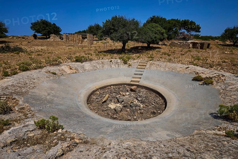Concrete crater in an arid landscape with scattered trees under a blue sky, Lost Place, Air Defence Position, Aerophone, Parabolic Acoustic Mirror, Patella Mountain, WW2, west of Lakki, Leros, Dodecanese, Greek Islands, Greece