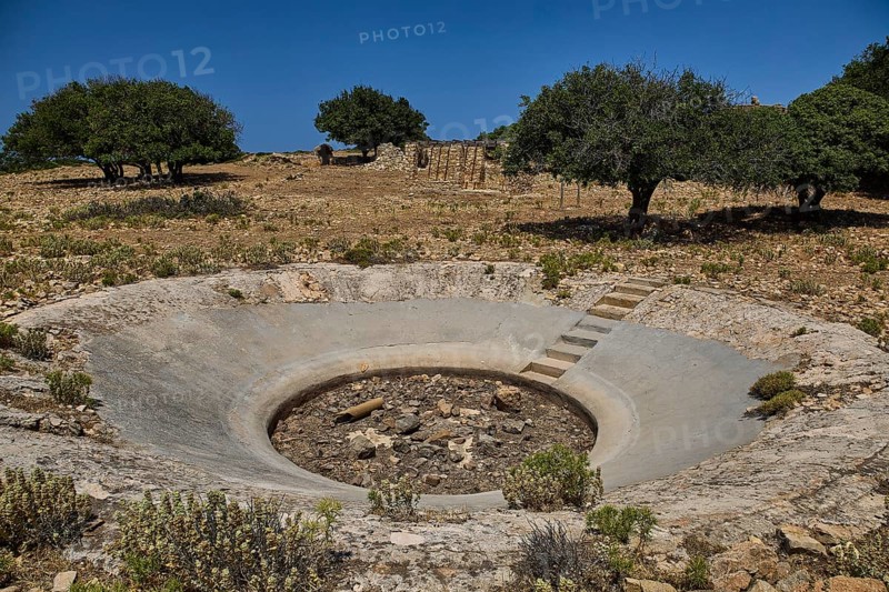 Crater in an arid environment with trees and stony ground under a blue sky, Lost Place, Air Defence Position, Aerophone, Parabolic Acoustic Mirror, Patella Mountain, WW2, west of Lakki, Leros, Dodecanese, Greek Islands, Greece