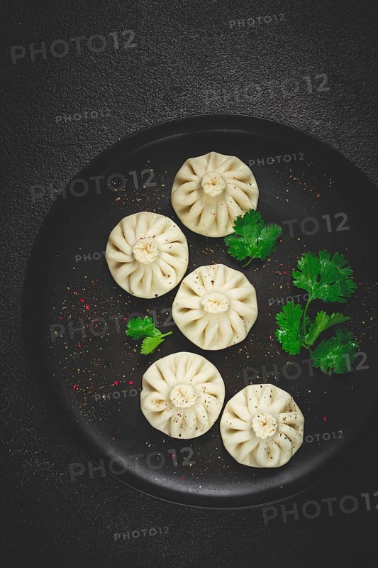 Khinkali, a traditional Georgian dish, with spices and herbs, top view, no people, on a black plate