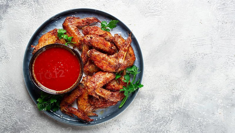 Fried in the oven, chicken wings, with spices, tomato sauce, on a plate, gray background, no people, homemade