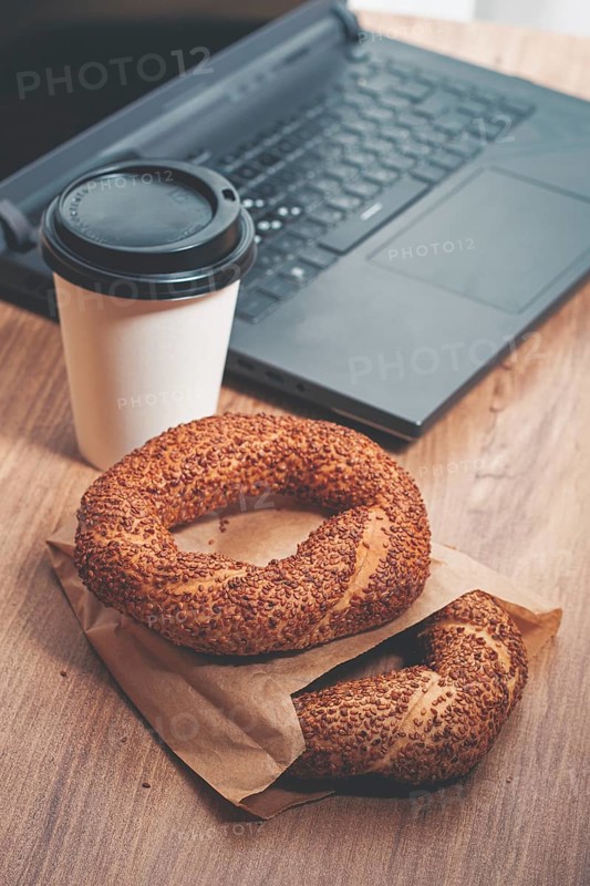Simits with coffee on a wooden table, with a laptop, in a cozy working environment, snack, breakfast, no people
