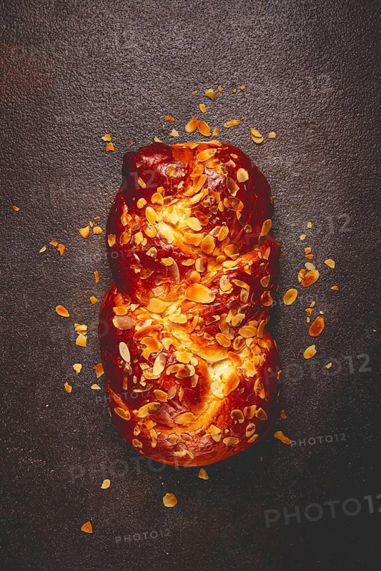 Braided, sweet bread pie, with sliced almonds, breakfast, braided bread, brioche, on a dark background, top view, no people
