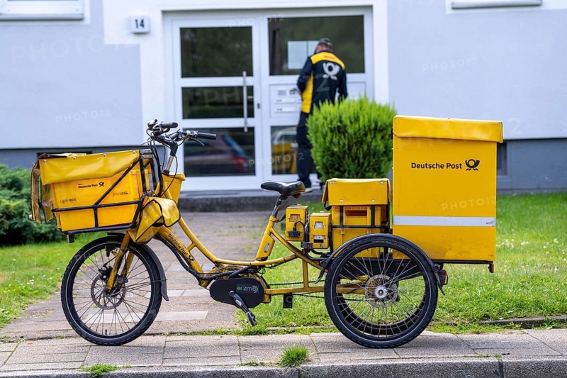 Postman, Deutsche Post, distributes the mail in an apartment building, electric tricycle, North Rhine-Westphalia, Germany