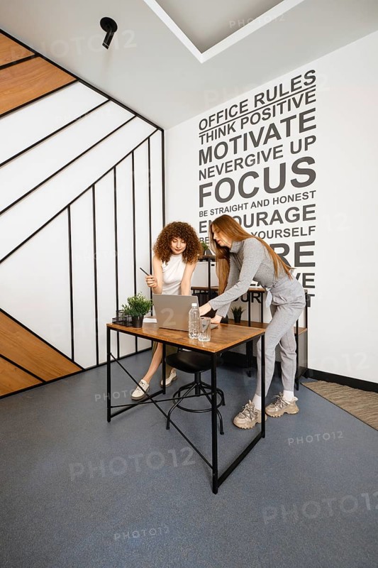 Two women work together in a stylish office dedicated to women's health, discussing plans and strategies