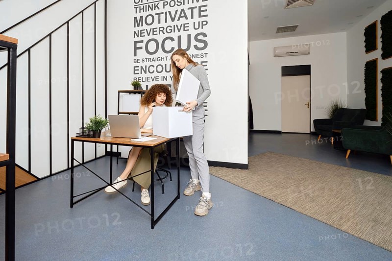 A woman looks into a box with the archives that her colleague brought to modern coworking