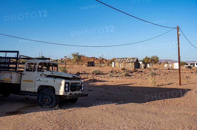 Old transport vehicle and simple houses made of wood and mud in a small village, Erongo, Damaraland, Namibia
