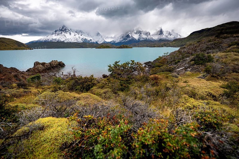 Cloudy mountain range Cuernos del Paine, shore of the blue lake Lago Pehoe in the evening light, dramatic sky, Torres del Paine National Park, Chile