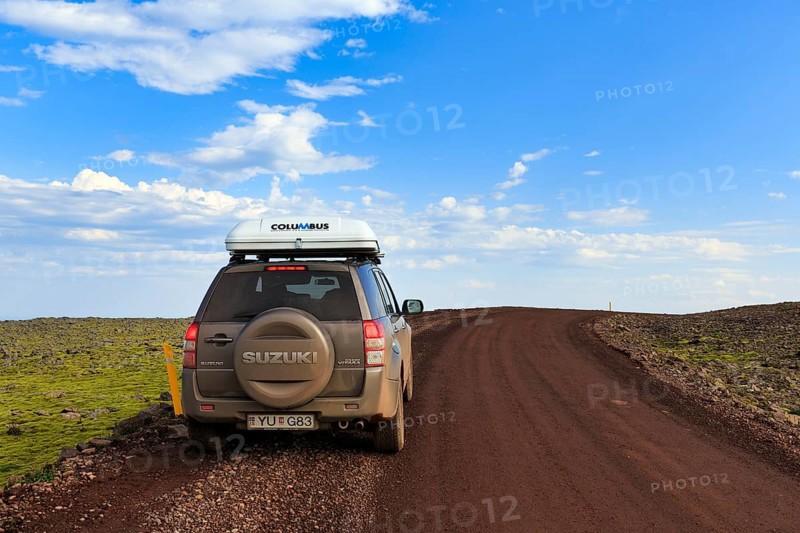 SUV Suzuki Grand Vitara with roof tent, travelling on a gravel road, Cumulus, Latrabjarg headland, Westfjords, Iceland
