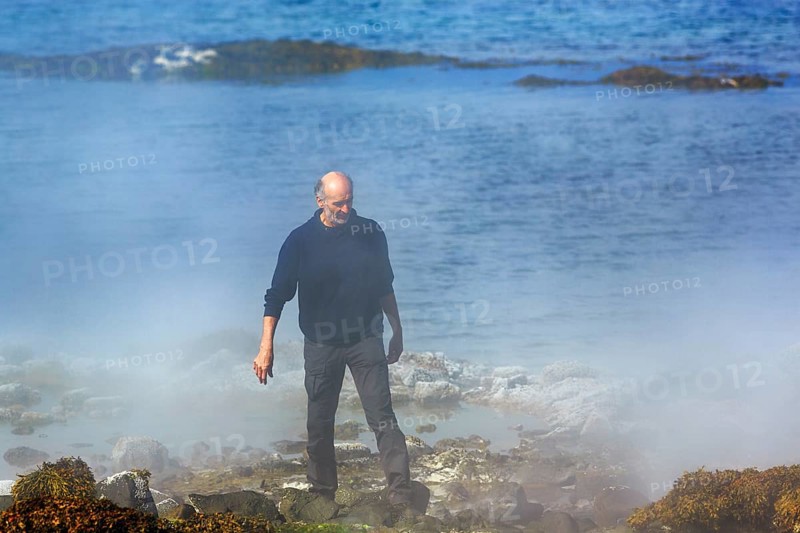 Hot spring flows into the sea, tourist on steaming rocky coast near Reykjanes, Súðavík, Ísafjarðardjúp fjord, Vestfirðir, Westfjords, Iceland