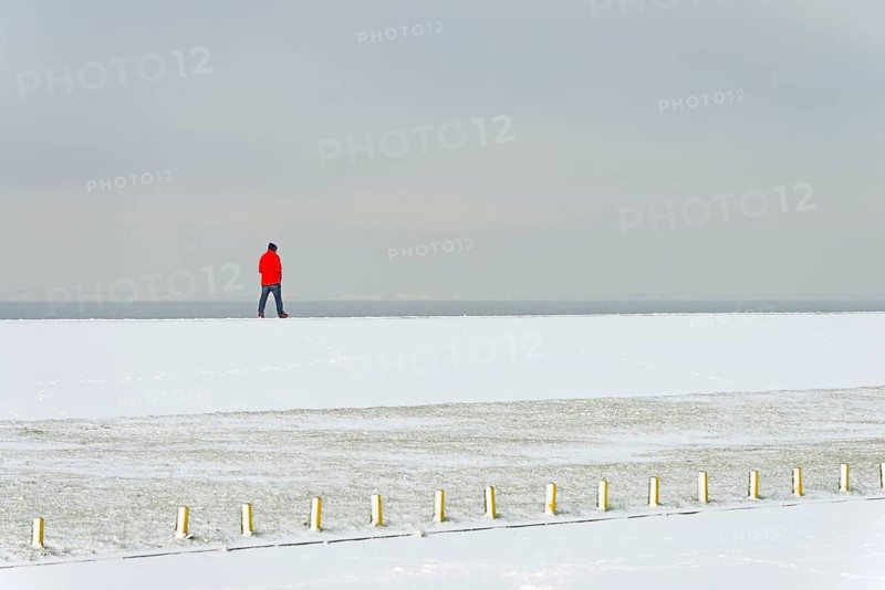 Winter day, onset of winter, snow on the North Sea coast, person walking over a dyke, North Sea, Norddeich, Lower Saxony, Germany