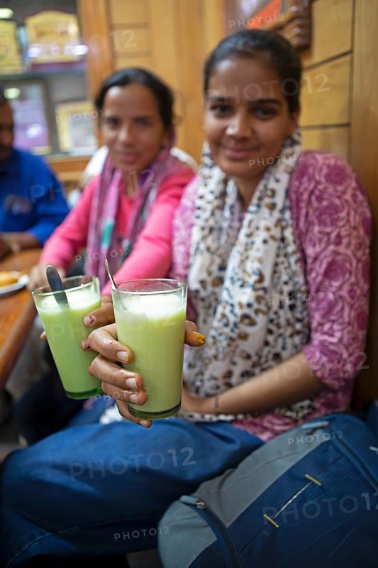 Indian blurred woman showing lassi or yoghurt drinks to the camera, Sandar Market Girdikot, old town of Jodhpur, Rajasthan, India
