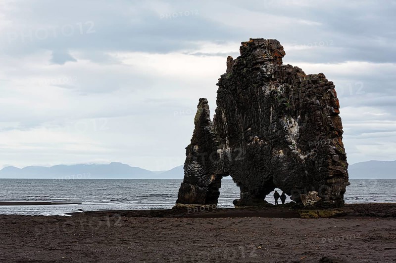 Tourists, couple at the basalt rock Hvitserkur, famous Elephant Rock at the lava beach, coastline, Vatnsnes peninsula, Hunafjördur, North Iceland, Iceland