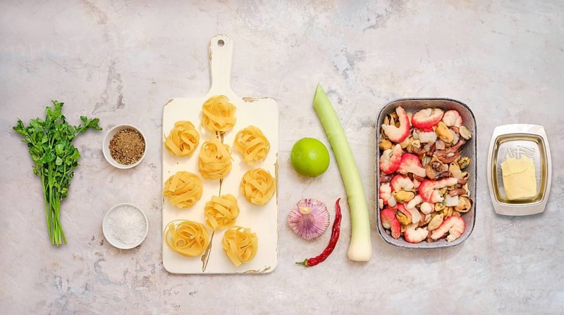 Fresh ingredients for fettuccine allo scoglio, including seafood, pasta, herbs, and vegetables. This colorful assembly showcases the vivid elements ready for cooking