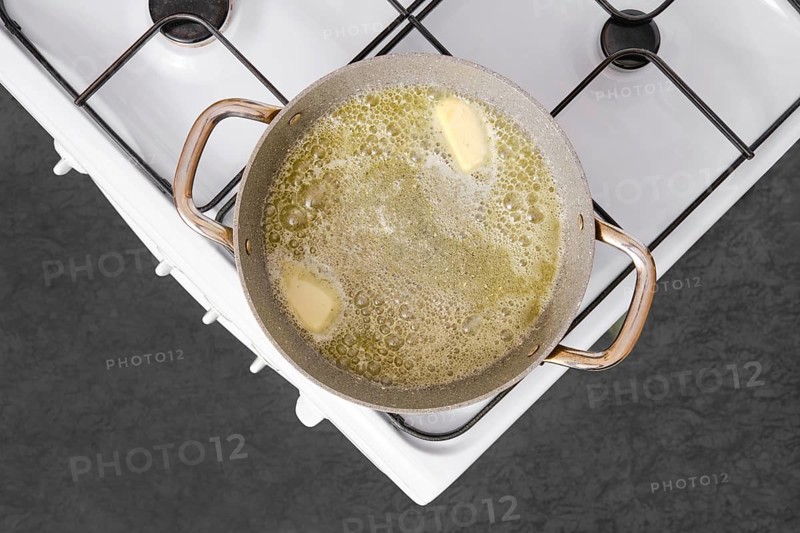 A pot on a stove is filled with melted butter, bubbling as it simmers. This is the starting point for preparing fettuccine allo scoglio, a flavorful seafood pasta dish