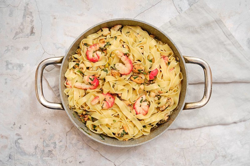Delicious fettuccine allo Scoglio presented in a rustic bowl, showcasing succulent seafood and fresh herbs. Perfectly cooked pasta is complemented by the vibrant flavors of shrimp and other seafood
