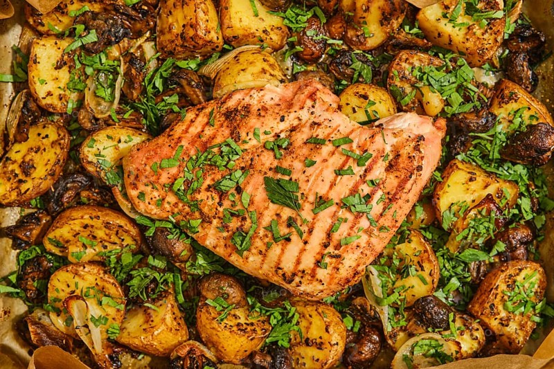 Juicy roasted turkey breast is perfectly cooked and garnished with fresh herbs, surrounded by golden seasoned potatoes and mushrooms