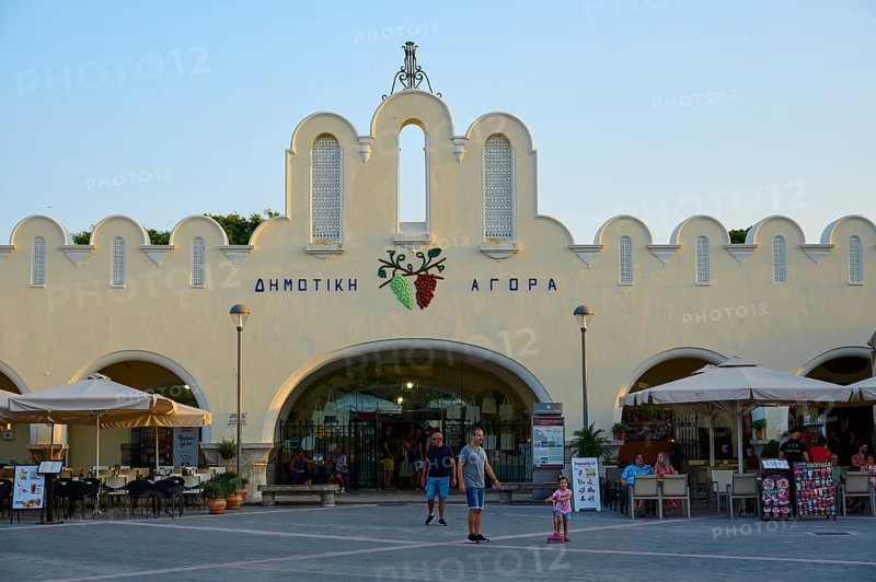 Agora, Municipal market hall, Lively market with white buildings and parasols in the foreground, Kos Town, Kos, Dodecanese, Greek Islands, Greece
