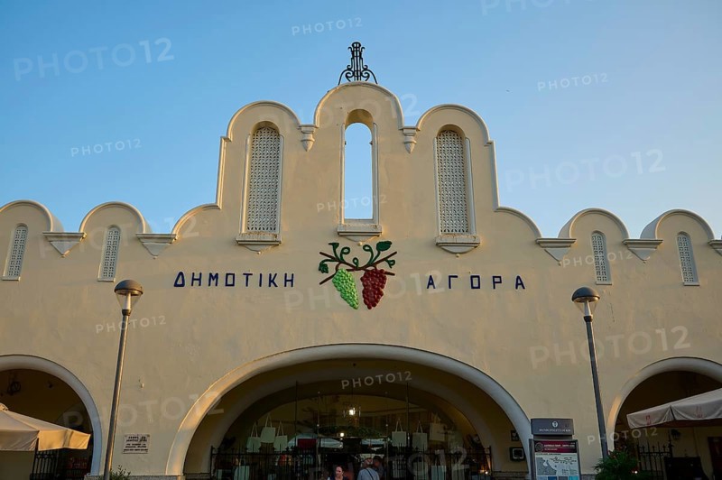 Agora, Municipal Market Hall, White market hall with Greek writing and grape emblem, illuminated by the evening sun, Kos Town, Kos, Dodecanese, Greek Islands, Greece