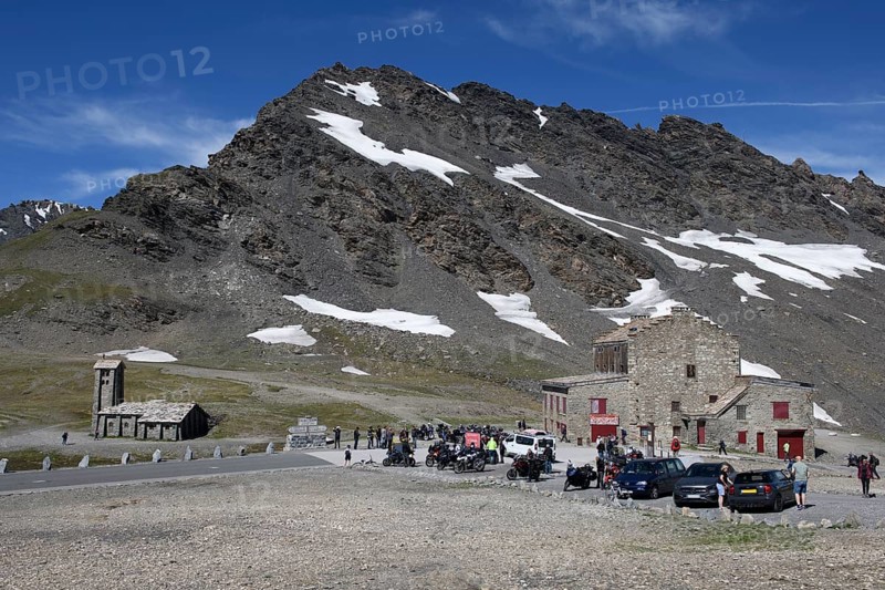 View of pass summit from pass road alpine road mountain road highest passable 2764 2770 metre high alpine pass Col de l'Iseran, in the foreground car park, on the left chapel Notre-Dame-de-Toute-Prudence. on the right building with restaurant, in the background 3041 metre high mountain peak Pointe des Lessières, Col de l'Iseran, department road D902, Route des Grandes Alpes, Département Savoie, Region Auvergne-Rhône-Alpes, Graian Alps, France